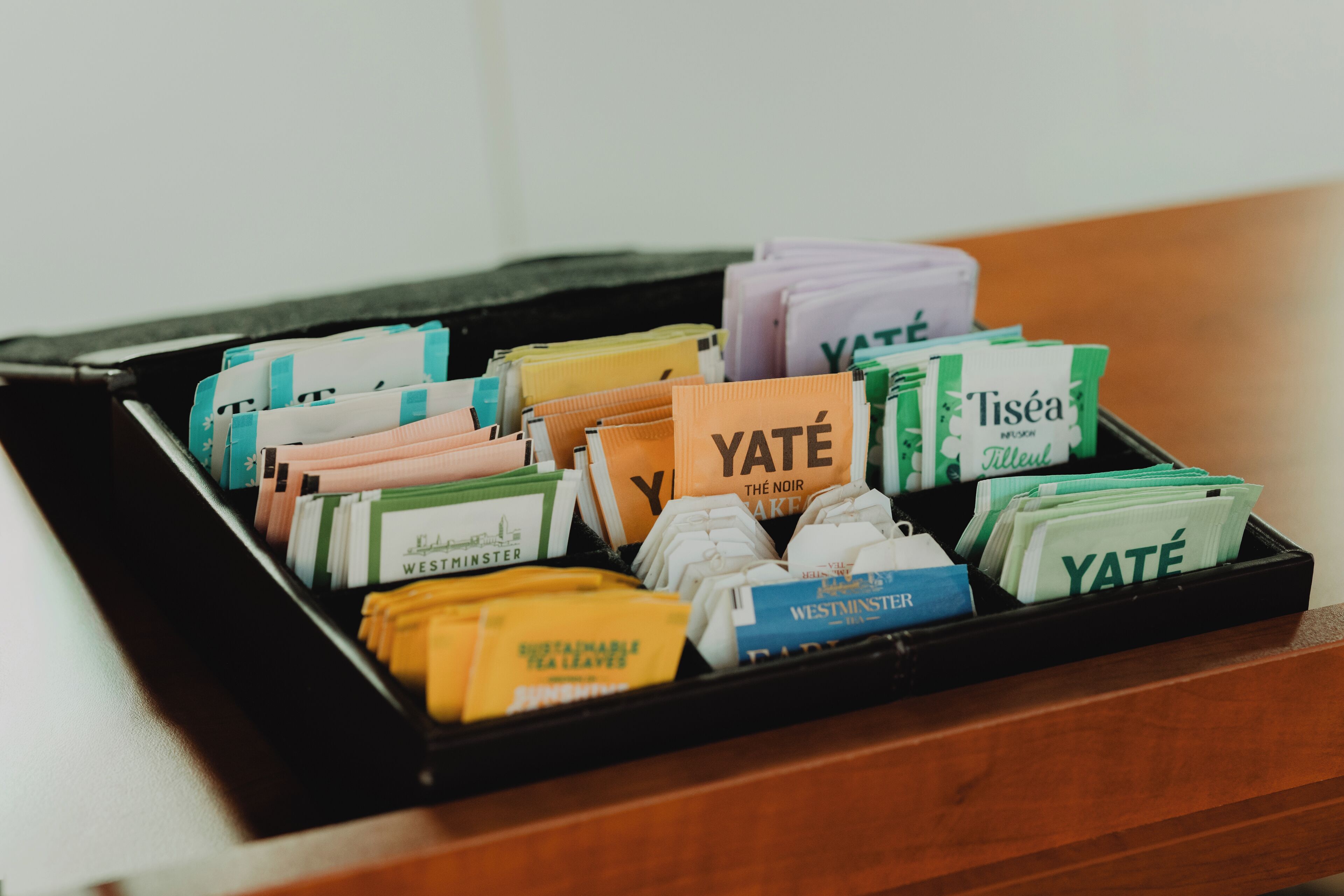 Un tiroir rempli de sachets de thé, soigneusement rangés et étiquetés avec différentes marques et différents noms.