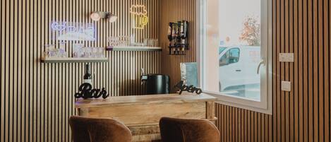 A bar area with wooden paneling, two leather chairs, a neon sign, and a window view.