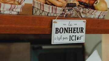 A buffet with various breads and pastries, including croissants and baguettes, displayed on wooden shelves.