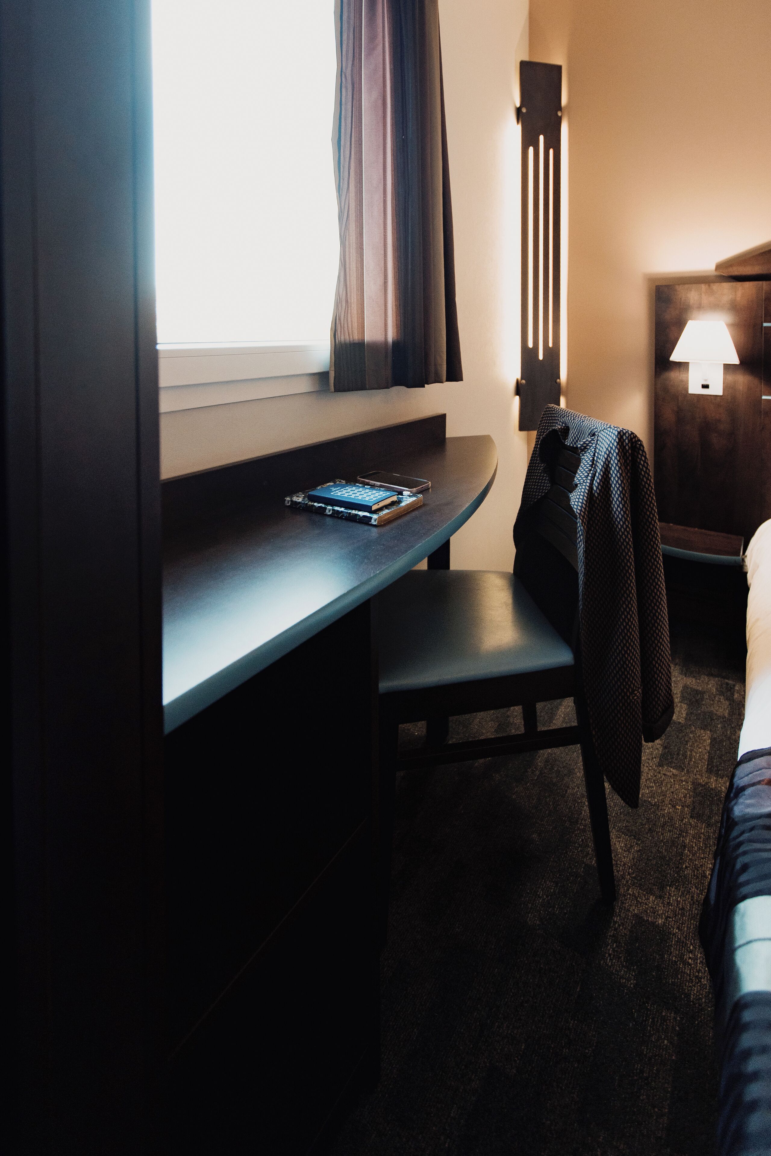 Ein Hotelzimmer mit Schreibtisch, Stuhl und Bett.
