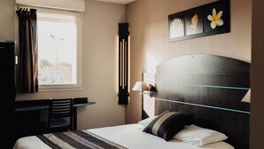 Habitación de hotel con una cama grande, un escritorio y una ventana con cortinas.
