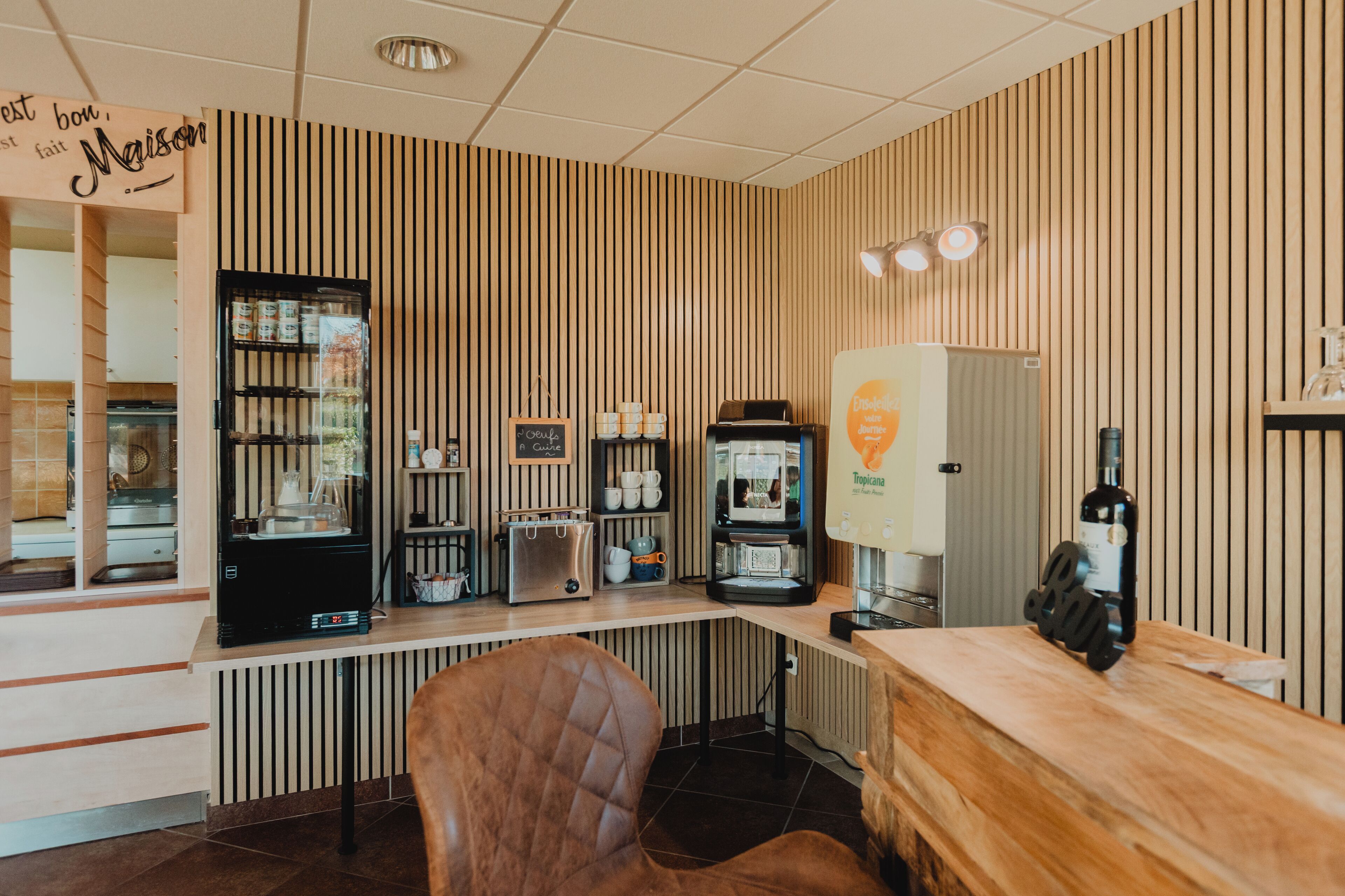 A café interior with a counter, seating, coffee machines, and a refrigerator.