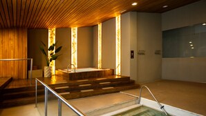 Un área de spa con un jacuzzi, escalones de madera y una piscina con fondo de cristal.