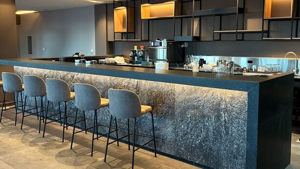 Una cocina moderna con una isla central, taburetes de bar y electrodomésticos integrados.
