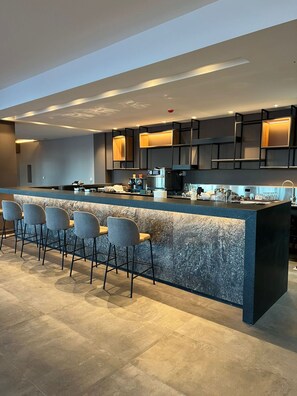 Una cocina moderna con una isla central, taburetes de bar y electrodomésticos integrados.