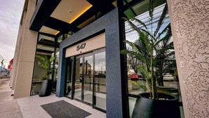 Un edificio moderno con entrada de vidrio, el número '547' sobre la puerta y plantas en macetas afuera.