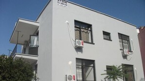 Un edificio moderno con numerosi balconi, condizionatori d'aria e una insegna che indica che si tratta di un hotel.