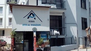 Un edificio a due piani con un cartello che riporta 'AYDIN OTEL & PANSIYON'.