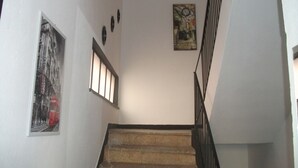 Una scala con corrimano, una finestra con persiane e un muro con quadri incorniciati.