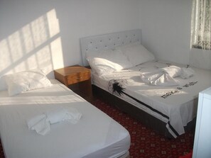 A hotel room with two single beds, a wooden nightstand, and a red patterned carpet. - Aydın Otel Pansiyon (Antalya)