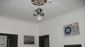 Una stanza con un lampadario, un quadro raffigurante un edificio e un oggetto decorativo con un simbolo a forma di occhio.
