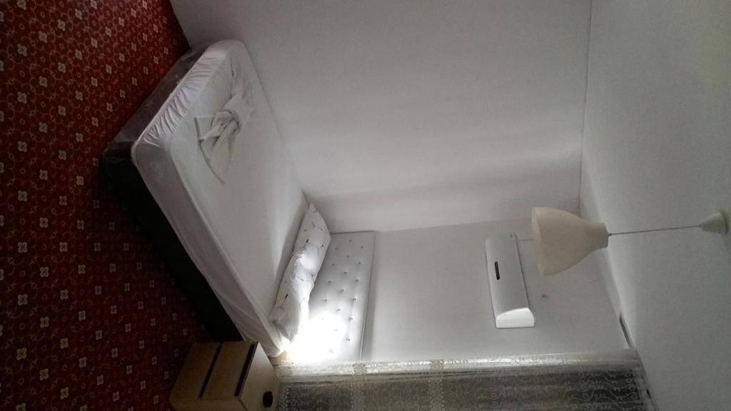 Een kamer met een bed, nachtkastje en lamp.