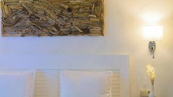 Un dormitorio con cama, almohadas, mesita de noche, lámpara de pared y un elemento decorativo en la pared.