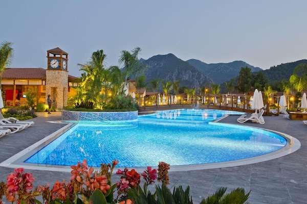 Una piscina al aire libre, sombrillas, sillones reclinables de piscina