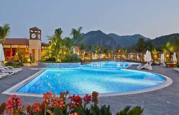 Una piscina al aire libre, sombrillas, sillones reclinables de piscina