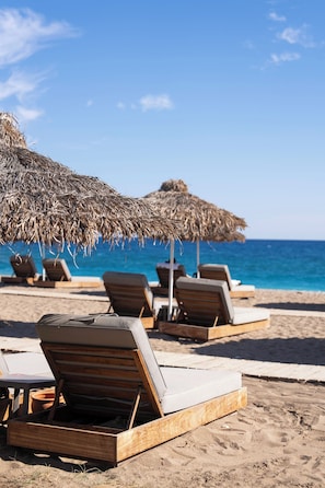A beachside lounge area with wooden lounge chairs and thatched umbrellas. - Kimera Lounge Hotel (Kemer)
