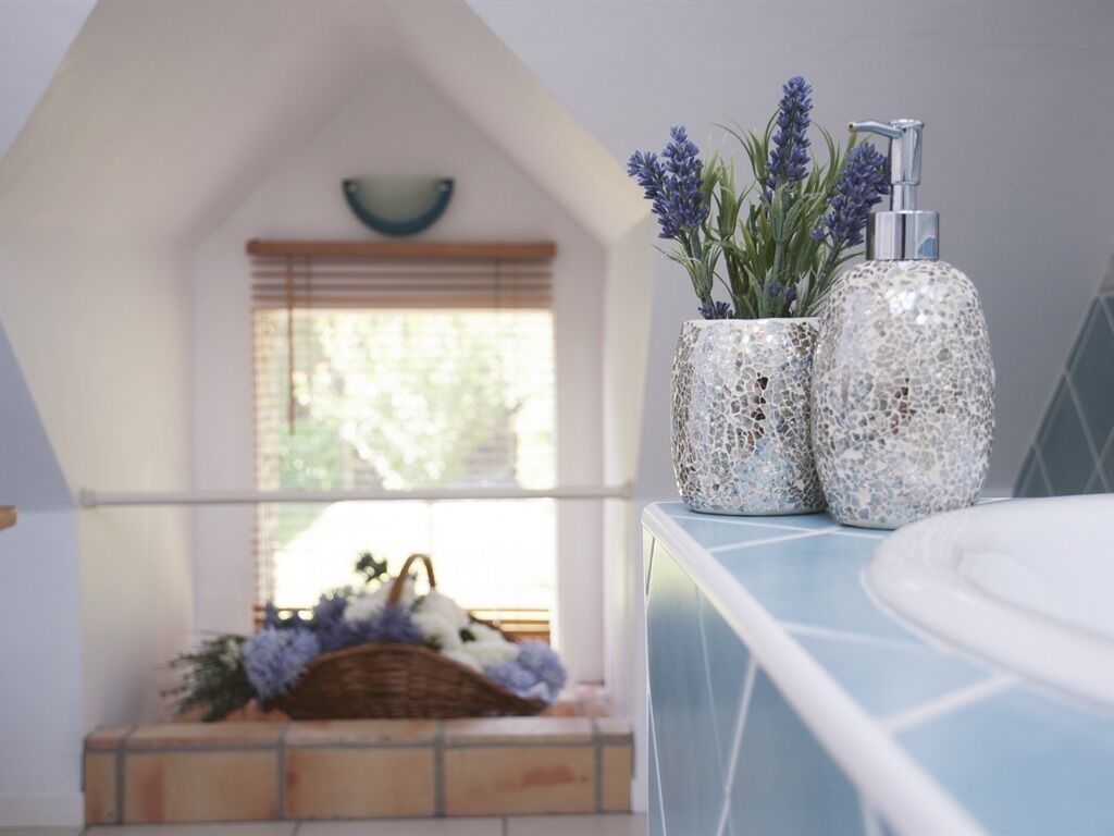 A bathroom with a blue countertop, a white sink, and two decorative vases with lavender plants.
