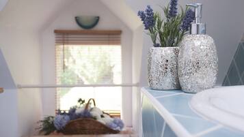 A bathroom with a blue countertop, a white sink, and two decorative vases with lavender plants.