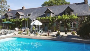 A pool area with a stone building, outdoor seating, and a pergola. - La Marmoire (Soudan)