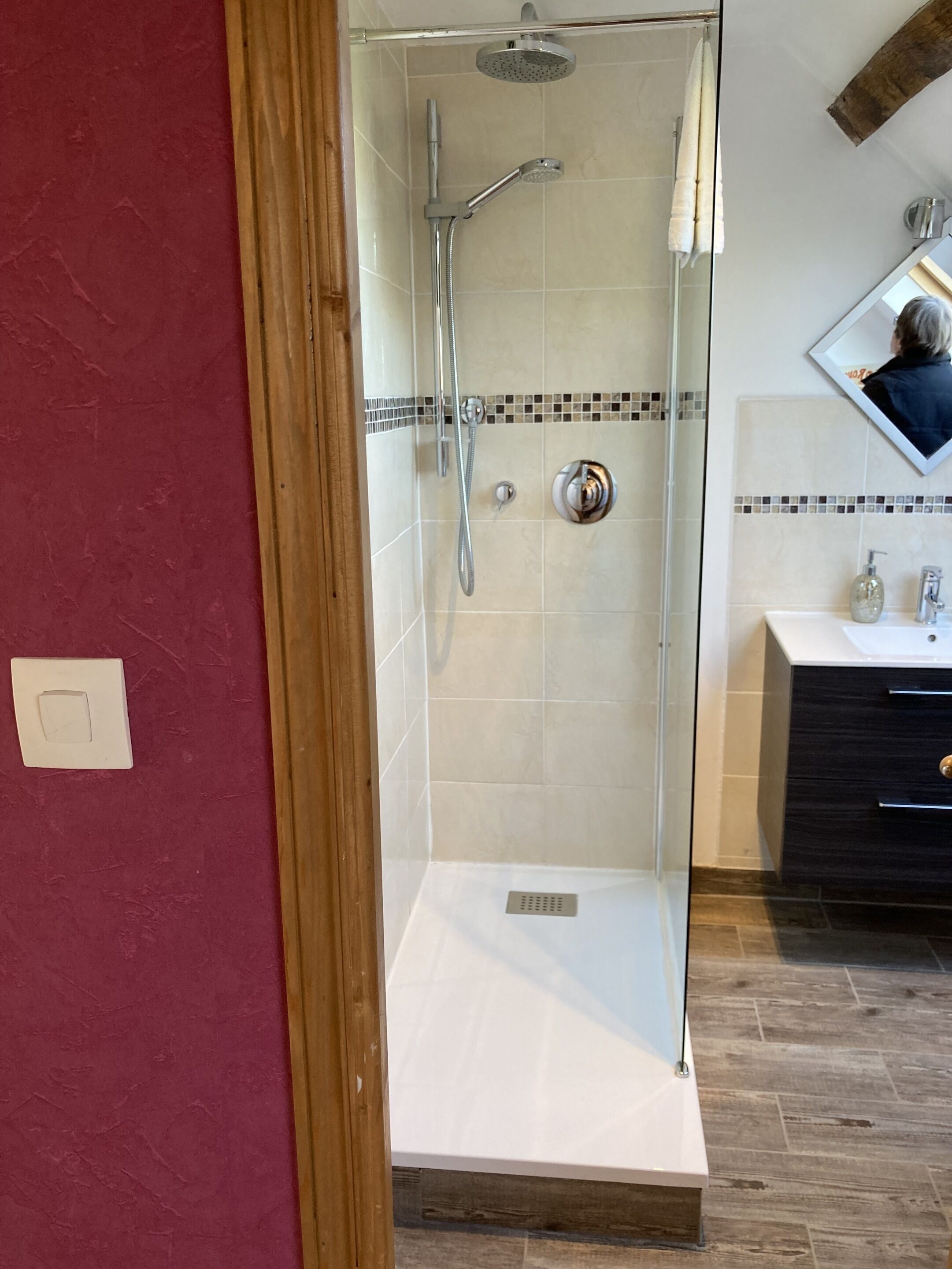 A modern bathroom with a glass-enclosed shower, a white sink, and a dark wooden cabinet.