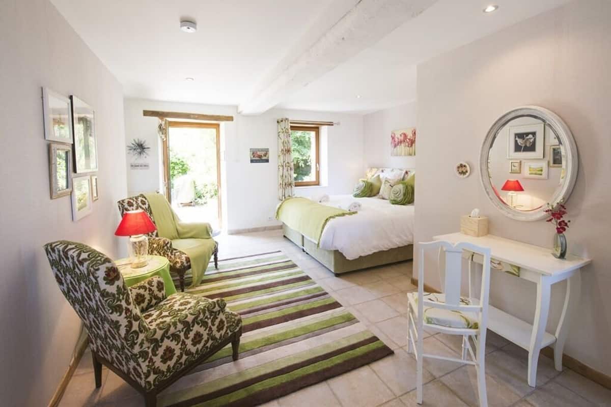 A bedroom with a bed, a desk, a chair, a lamp, and a mirror.