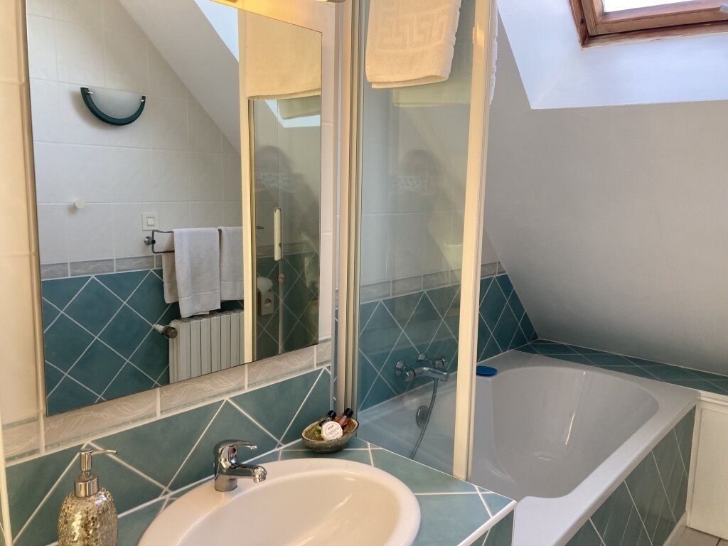 Une salle de bain avec une baignoire, un lavabo et un miroir.