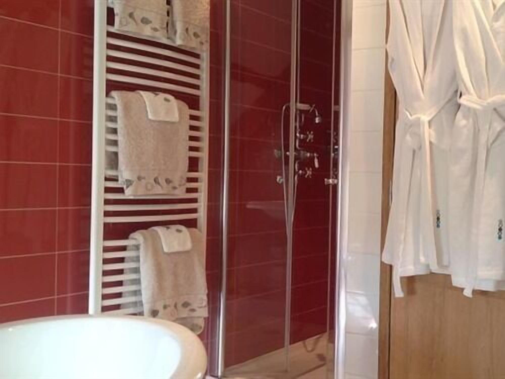 A bathroom with a glass-enclosed shower, a white sink, and a towel rack with multiple towels.
