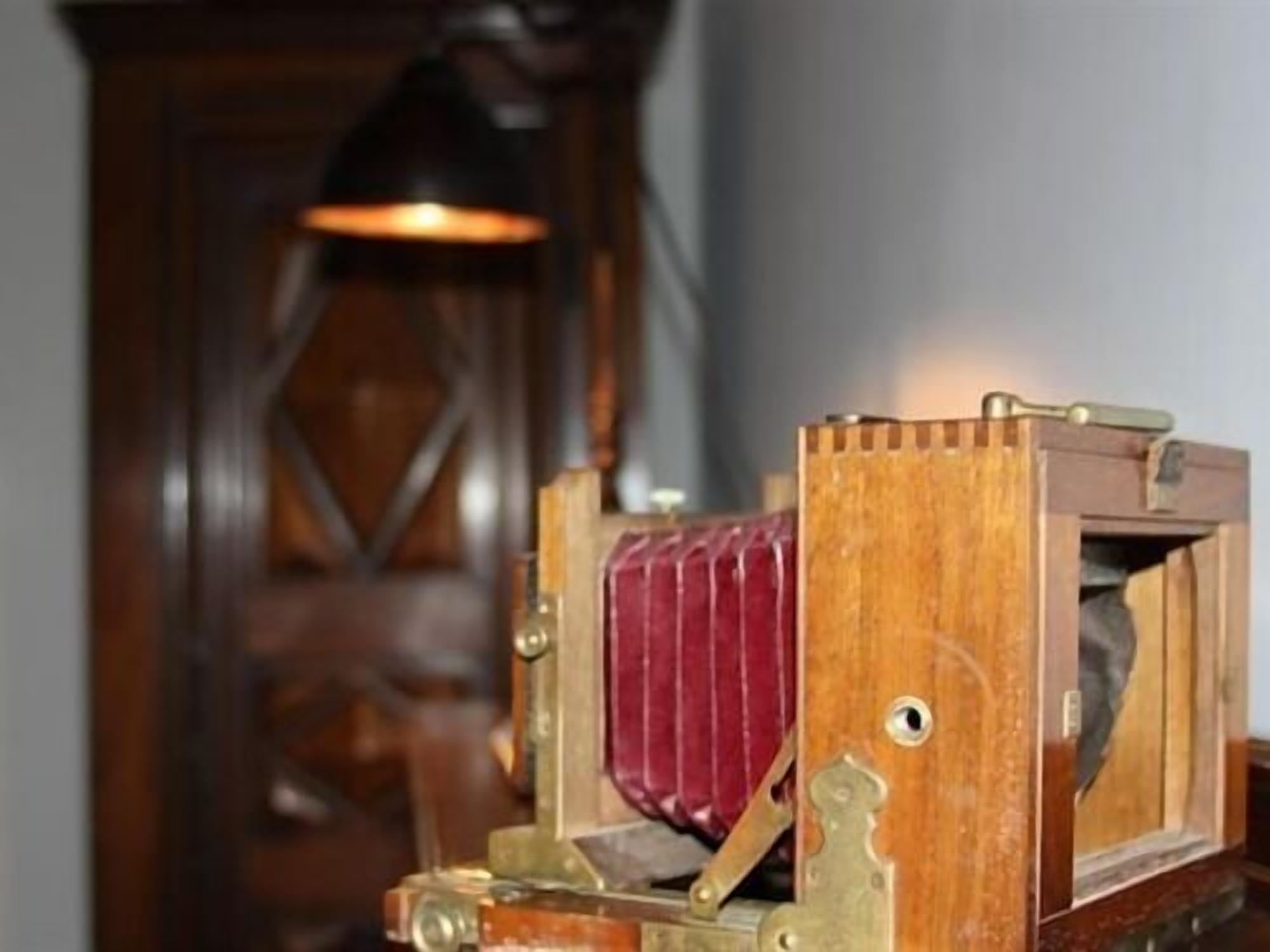 Een oud mechanisch apparaat, mogelijk een camera, met een houten frame en messing onderdelen.
