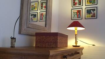 A wooden dresser with a mirror above it and a lamp on top. There are framed pictures on the wall behind the dresser.
