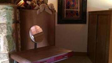 A wooden vanity with a mirror, a small drawer, and a shelf with stuffed animals.