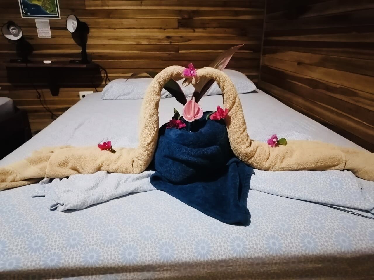 A neatly made bed with towels and flowers arranged in a decorative manner.