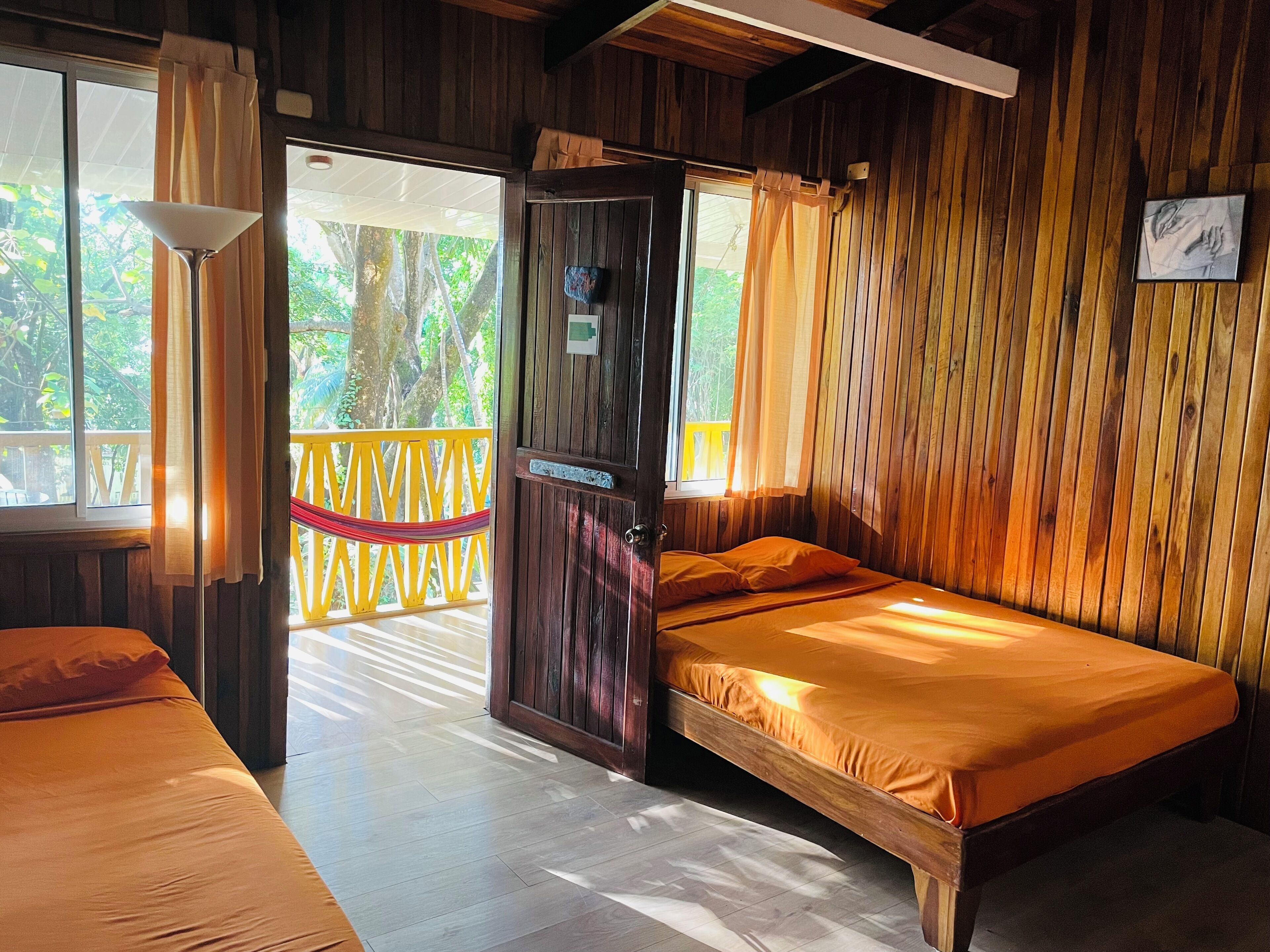 A wooden room with a bed, a door, and a window.