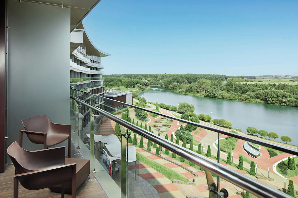 Un balcon moderne donnant sur un fleuve et des jardins aménagés.