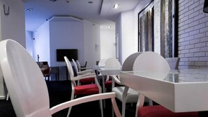 A conference room with a glass table and white chairs with red cushions. - Eter Hotel (Niš)