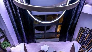 A modern interior with a circular light fixture, a staircase, and a dining area with yellow chairs.