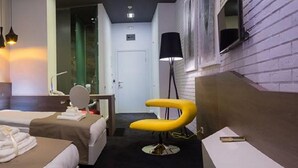 A hotel room with two beds, a bathroom mirror, a yellow chair, and a bedside table. - Eter Hotel (Niš)