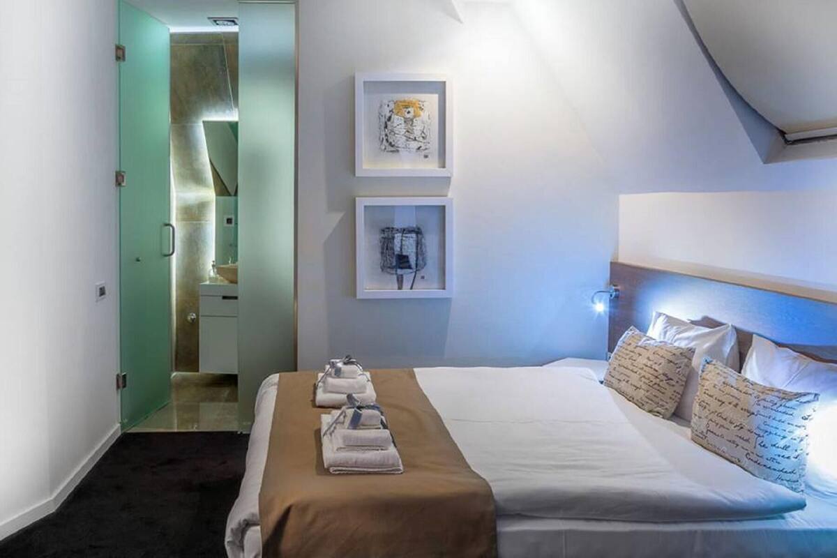 A hotel room with a bed, a bathroom, and a small art display on the wall.