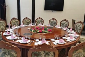 A round dining table with chairs, a floral centerpiece, and a flat-screen TV mounted on the wall. - Xingyue International Hotel (Xianghuli Cultural Creative Ancient Street) (Ganzhou)