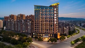 A modern hotel with a prominent glass facade, multiple floors, and a well-lit entrance. - Xingyue International Hotel (Xianghuli Cultural Creative Ancient Street) (Ganzhou)