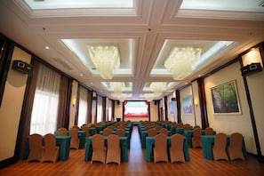 A conference room with rows of chairs, a stage at the front, and chandeliers. - Xingyue International Hotel (Xianghuli Cultural Creative Ancient Street) (Ganzhou)