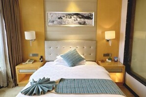A hotel room with a large bed, two bedside tables, a mounted artwork, and a window. - Xingyue International Hotel (Xianghuli Cultural Creative Ancient Street) (Ganzhou)