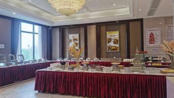 A banquet hall with a long table, chairs, and a chandelier.