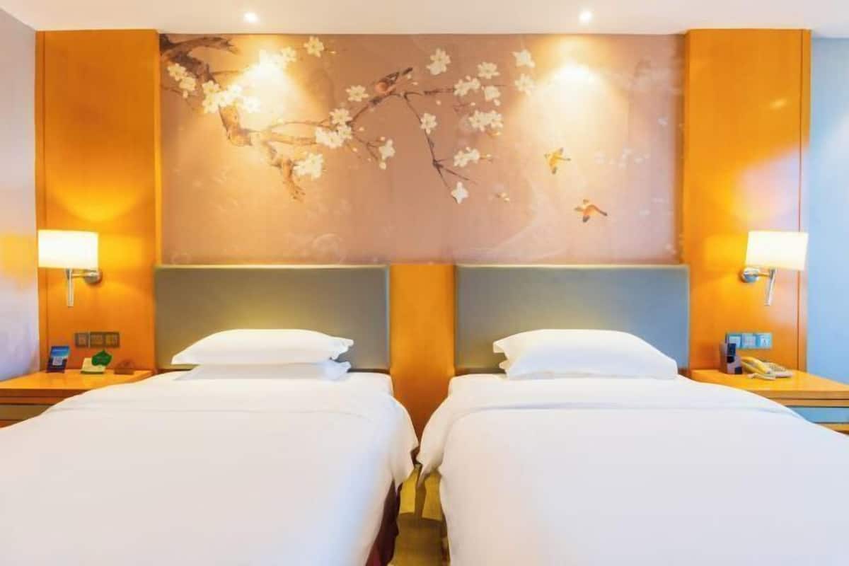 A hotel room with two beds, a wall mural, and bedside lamps.