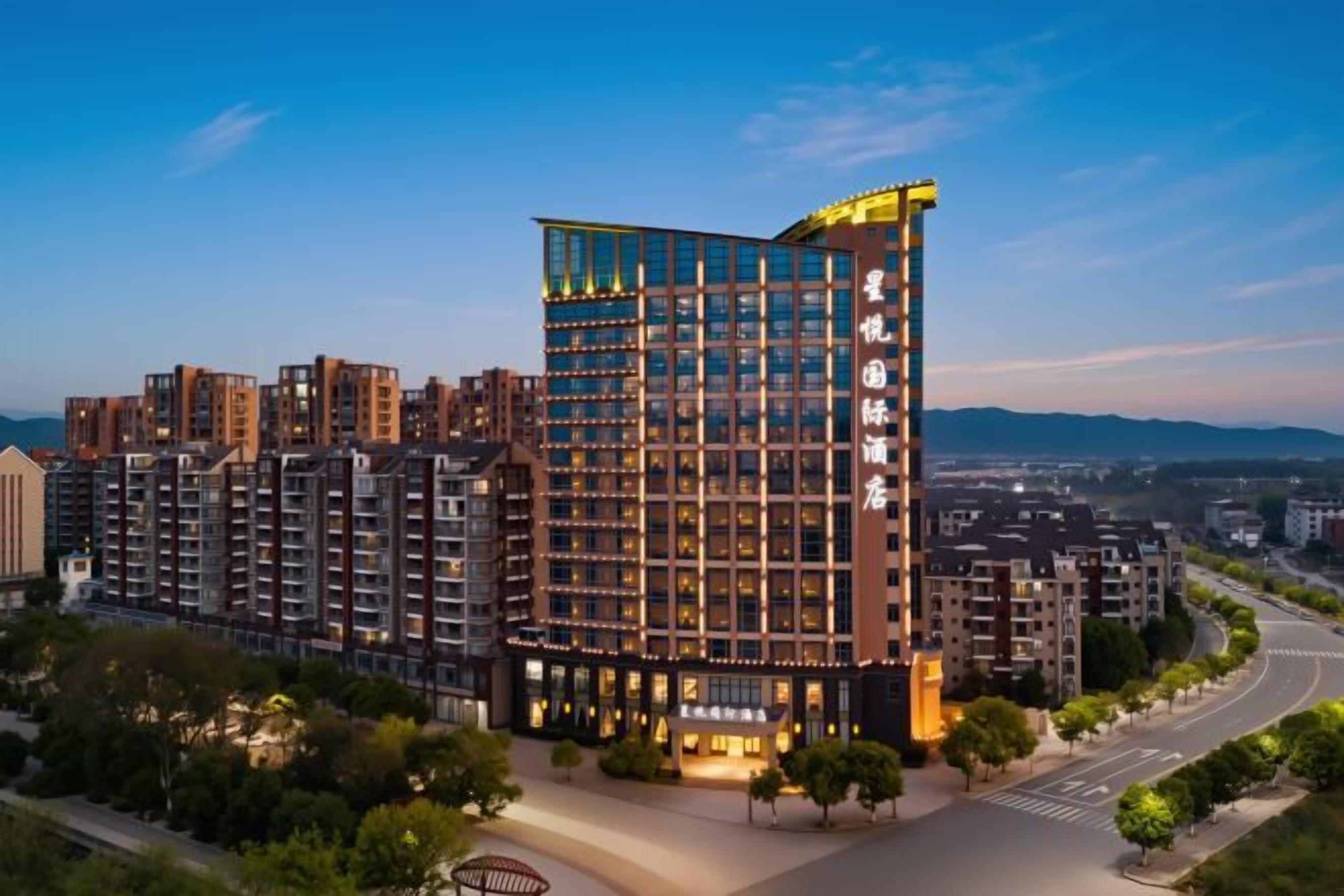 A multi-story hotel with a modern design, featuring a prominent glass facade and a rooftop terrace.