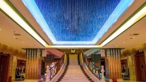 A grand staircase with a modern design, leading to a high-ceilinged area with a unique light feature. - Xingyue International Hotel (Xianghuli Cultural Creative Ancient Street) (Ganzhou)