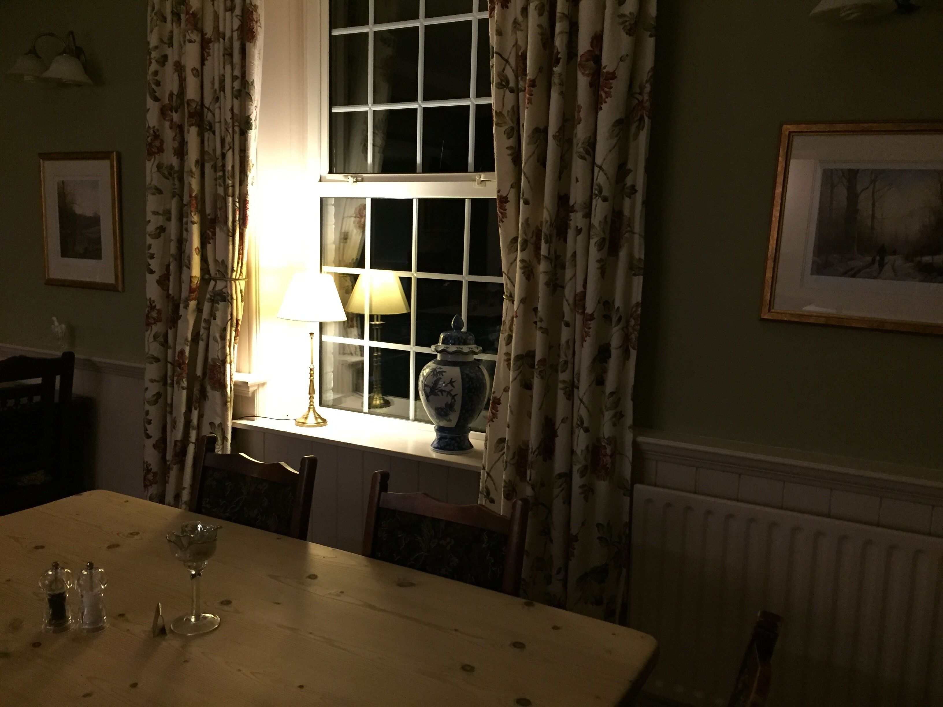 A dining area with a table, chairs, a vase, and a lamp.