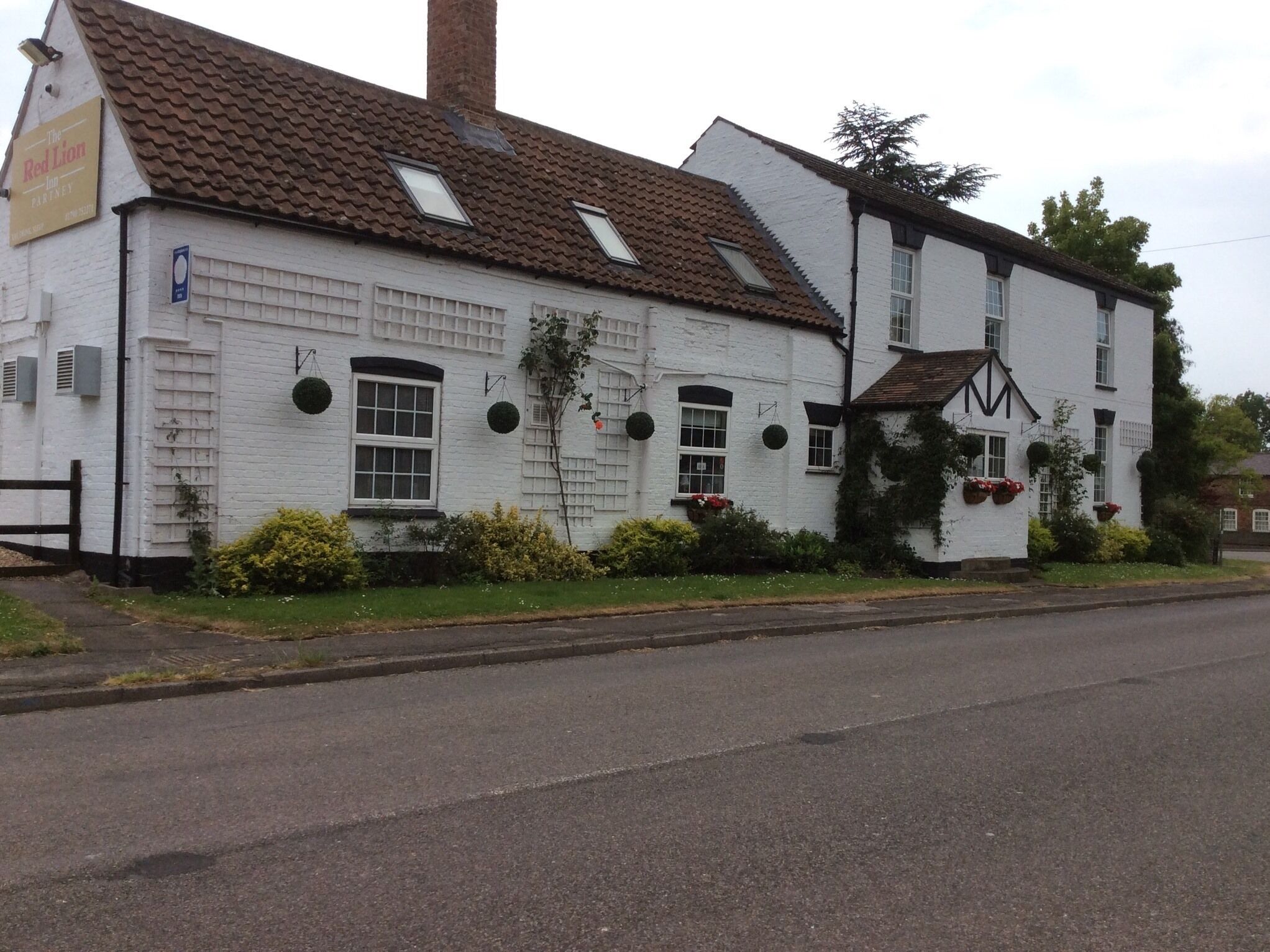 A white building with a tiled roof, multiple windows, and a sign for 'The Red Lion Inn'.