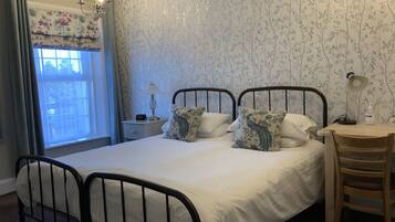 A bedroom with a double bed, two bedside tables, a desk, and a chair.