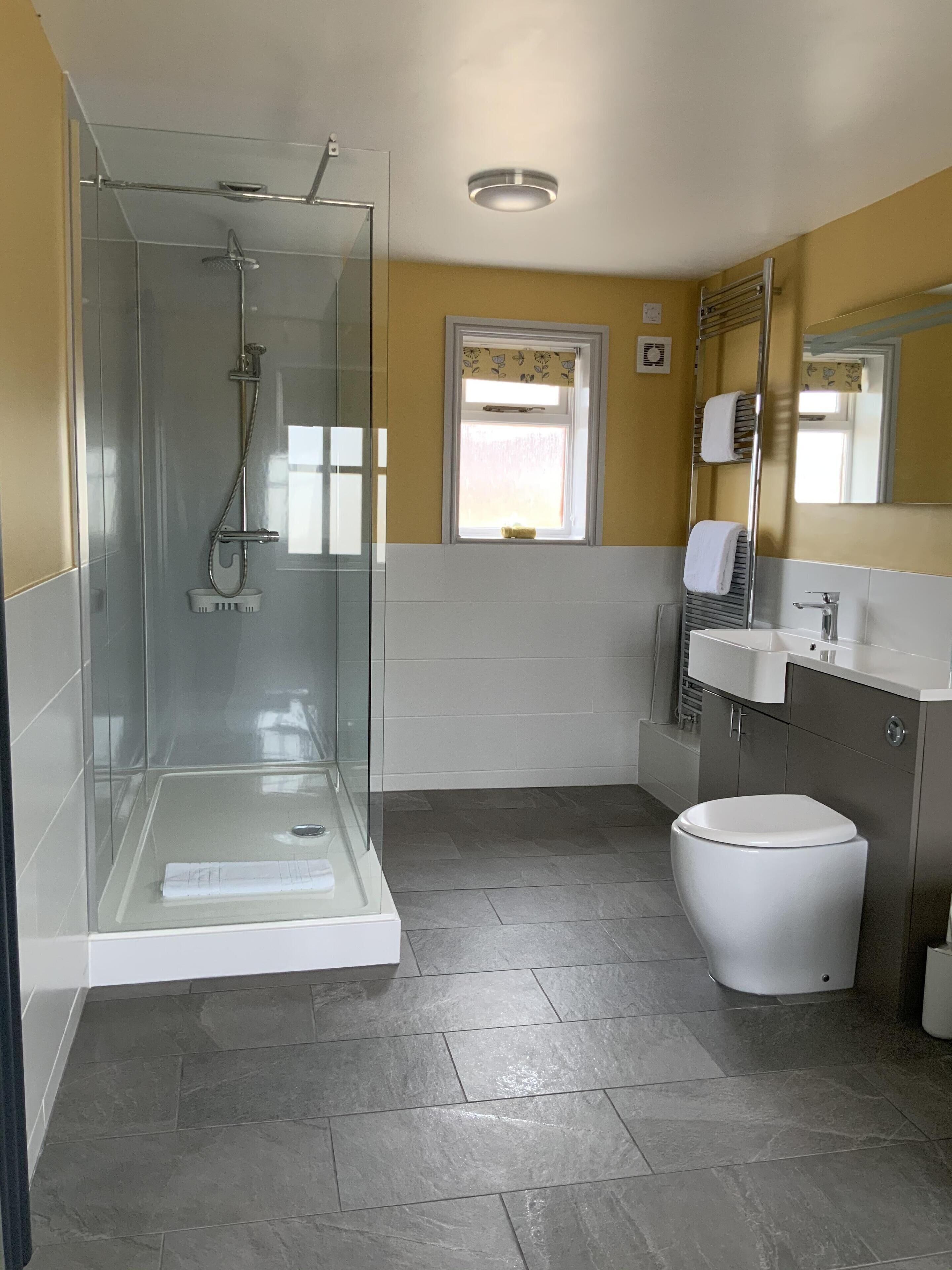 Un baño moderno con cabina de ducha de vidrio, un inodoro, un lavabo y un espejo.