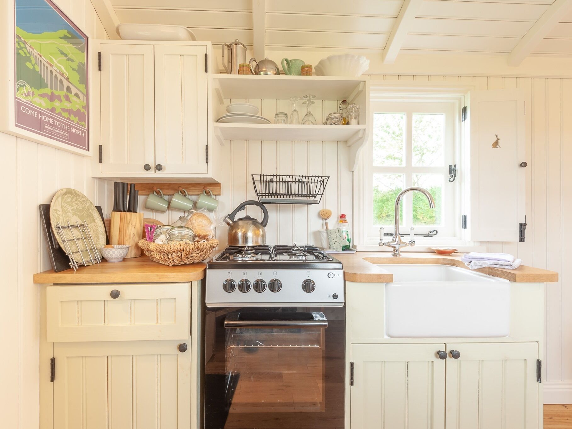 A kitchen with white cabinets, a stove, an oven, and a window with a view of greenery.
